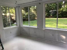 an empty room with three windows and a ladder