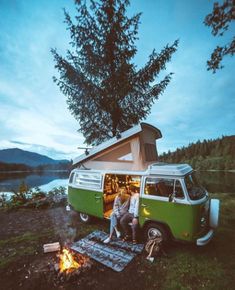 two people are standing in front of a camper van with the door open while it's lit up