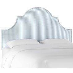 an upholstered headboard on a bed with white sheets and blue pinstripe