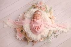 a newborn baby is wrapped in pink and surrounded by flowers