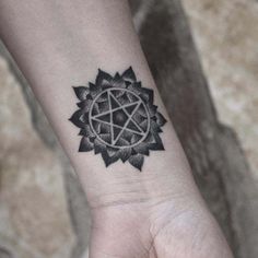 a black and white tattoo on the wrist of a person with a pentagramil