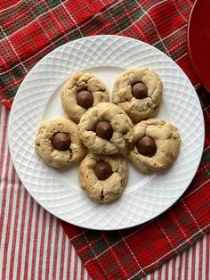 chocolate chip cookies on a white plate next to a red and green plaid tablecloth