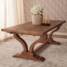 a wooden table sitting on top of a carpeted floor next to a vase with flowers