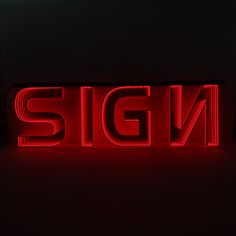 the word sign is lit up with red light in front of black wall and floor