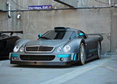 two sports cars parked next to each other in a parking lot with the doors open