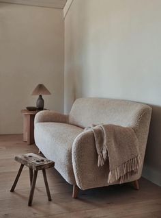 a couch with a blanket on it next to a small table and lamp in a room