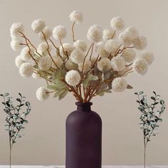 a purple vase with white flowers in it on a table next to two smaller ones