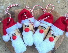 three santa clause ornaments are on a wooden slice with candy canes in the shape of santa's faces