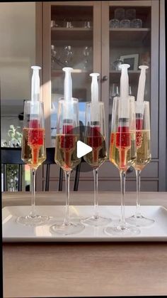 four wine glasses filled with different wines on a white tray in front of a glass cabinet