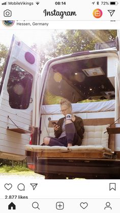 a man sitting in the back of a truck looking at his cell phone while holding a camera