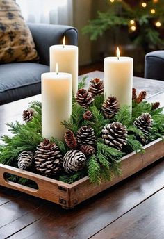 a tray with pine cones and candles in it on a table next to a couch