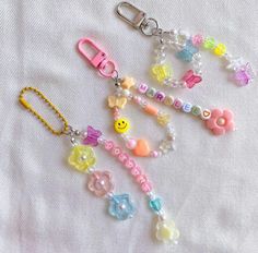 a key chain with beads and charms attached to it on a white sheet, next to a pair of scissors