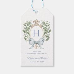 a white gift tag with the letter h on it and a blue ribbon tied around it