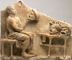 an ancient sculpture of a man sitting at a table