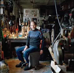 a man sitting on a chair in a room full of tools