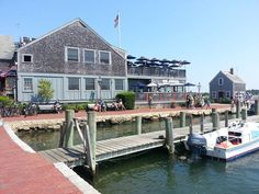 a boat is docked in the water next to a dock with people walking on it