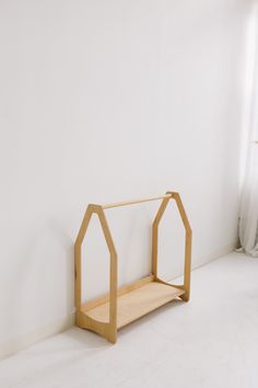 a wooden shelf sitting on top of a white floor next to a window in a room