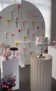 there is a display with flowers on the wall and desserts on the table in front of it