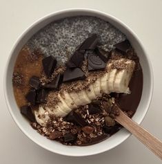 a bowl filled with oatmeal, chocolate and banana slices next to a spoon