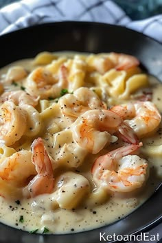 pasta with shrimp and cream sauce in a black bowl