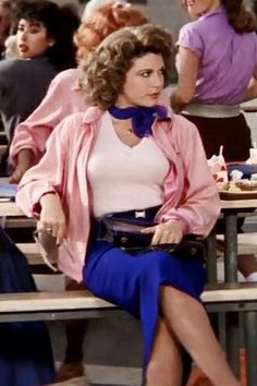 a woman sitting on top of a wooden bench next to other women in the background