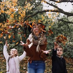 a woman and two children throwing leaves in the air