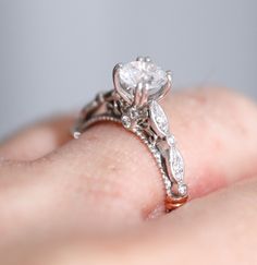 a close up of a person's hand with a diamond ring on their finger