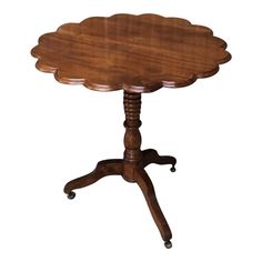 a small wooden table with wheels on the legs and a flower shaped center piece at the top