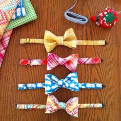 six bow ties laid out on a wooden table next to other accessories and items that include an ornament