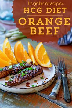 steak with oranges and asparagus on a plate next to utensils