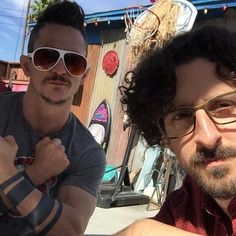 two men sitting next to each other in front of a basketball hoop with sunglasses on