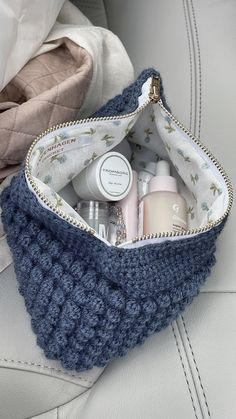 a blue purse filled with personal care items sitting on top of a white leather couch