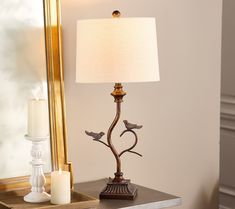 a lamp sitting on top of a wooden table next to a mirror and candle holder