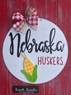 a wooden sign that says nebraska huskes with a red and white checkered bow on it