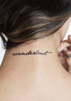 a woman's neck with the word wanderlust tattooed on her left side