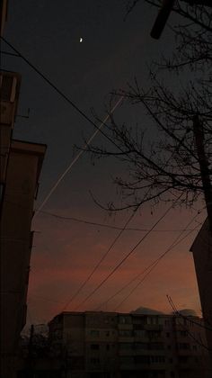 the sun is setting over some buildings and power lines