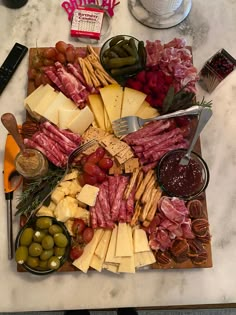 an assortment of cheeses, meats, and olives on a platter