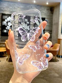 a woman holding up a clear case with butterflies on it