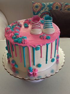 a cake with pink, blue and white icing that has shoes on top of it