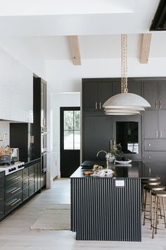 a large kitchen with black cabinets and an island