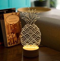 a pineapple shaped lamp sitting on top of a wooden table next to a book