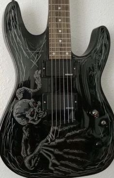 an electric guitar with black paint on it's body and neck, hanging from the wall