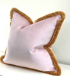 a pink and brown pillow sitting on top of a white table