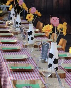 there are many vases with flowers in them sitting on the long table set for dinner