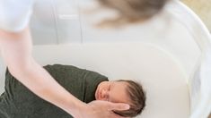 a baby is sleeping in a white crib with its hand on it's head