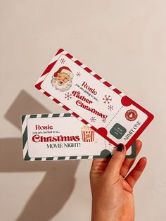 someone holding up two christmas gift cards with santa's face on one and another