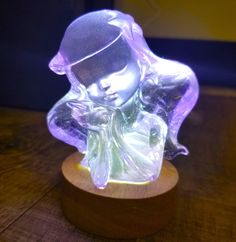 a glass figurine sitting on top of a wooden table next to a light