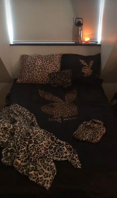 a leopard print comforter on a bed next to a night stand with a lit candle