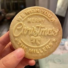 a hand holding a cookie that says we wish you merry christmas at the millers