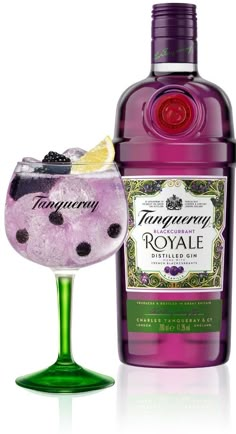 a bottle of ginny royale next to a glass filled with blueberries and lime